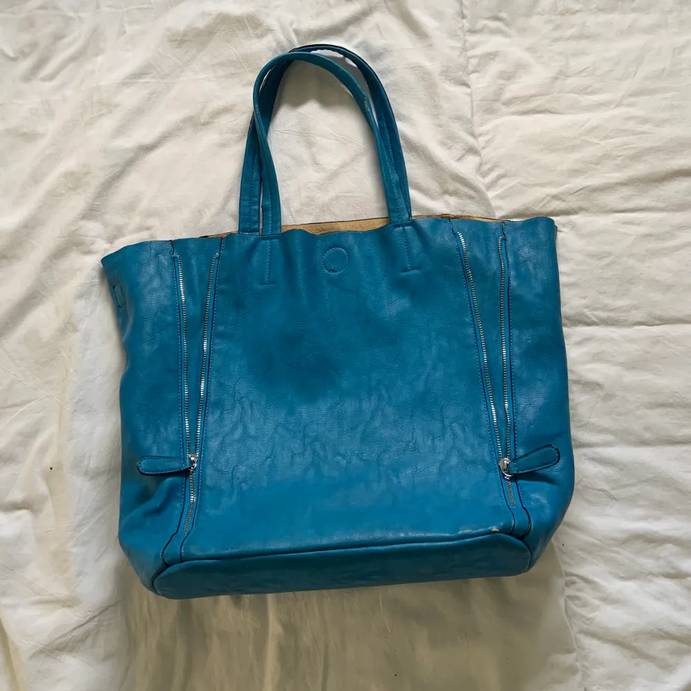 Skitsnygg blå handväska med dödskalle i nitar. Några nitar har ramlat av då den har legat i trångt utrymme pga sällan använd. . Väskor.
