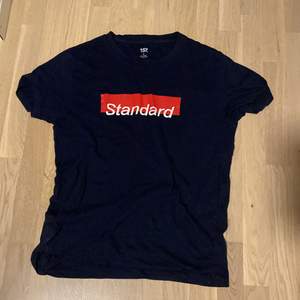 Mörkblå t shirt med texten ”standard”