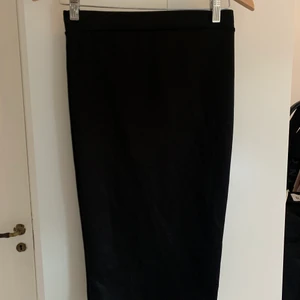 Svart kjol  - Svart kjol som går en bit nedanför knäna, sitter åt. 