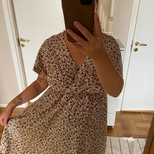 Blommig klänning - Vit klänning med bruna blommor. Jätteskön och luftig. Sitter bra. Köpt via denna appen, jag har inte använt den. 