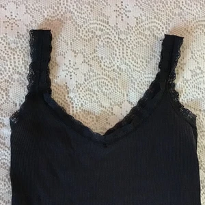 svart linne med spets - ett tajt ribbat linne med spets axelband som går runt hela uringningen <3 skicket är bra. köpt second hand. Skriv för bild på <3 Då många var intresserade har jag startat budgivning :)