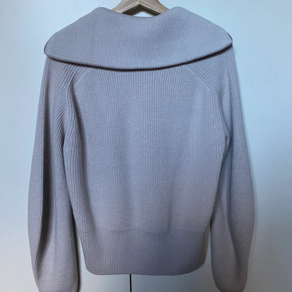 Ljusbeige/grå stickad tröja med lång krage och half-zip, något oversize modell. Använd endast ett fåtal gånger och i väldigt bra skick 🤎. Neuleet.