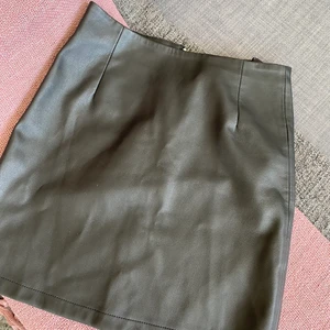 Skinn kjol  - Svart kort skinnkjol med kort dragkedja där bak från BIKBOK 