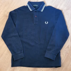 Fred Perry  - Fred Perry långärmad piké i mörkblått. Storlek 152 ca, 12 år. Bra skick, lite tvättpåverkad bara.