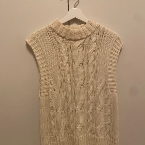 Stickad väst Ginatricot - En fin kabelstickad väst från ginatricot, endast använd 1 gång Storlek S (Notera att ljuset är gult) 