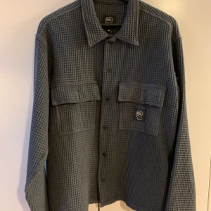 Brain dead overshirt waffle grå S - Grå overshirt med ”waffle” mönster. Använd och sliten av ryggsäcken dessvärre 