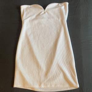 En skitsnygg vit kortklänning perfekt för utekvällar. Snygg v-ringning vid bröstet. Helt oanvänd! (Slimfit)