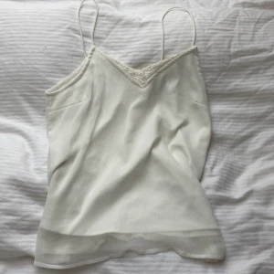 Vero Moda linne - Ett fint vit linne med mönster runt halsen samt ryggen. Till detta plagg kan du ha ett par svata kostym byxor eller ett par bekväm mjukisbyxkor.