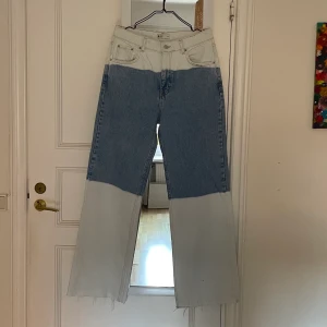 Jeans strl 40 - Jeans i storlek M från Ginatricot. Tvåfärgade. Hellånga vida byxben med avklippt benslut. Medelhög midja. Använda en gång, i gott skick. 