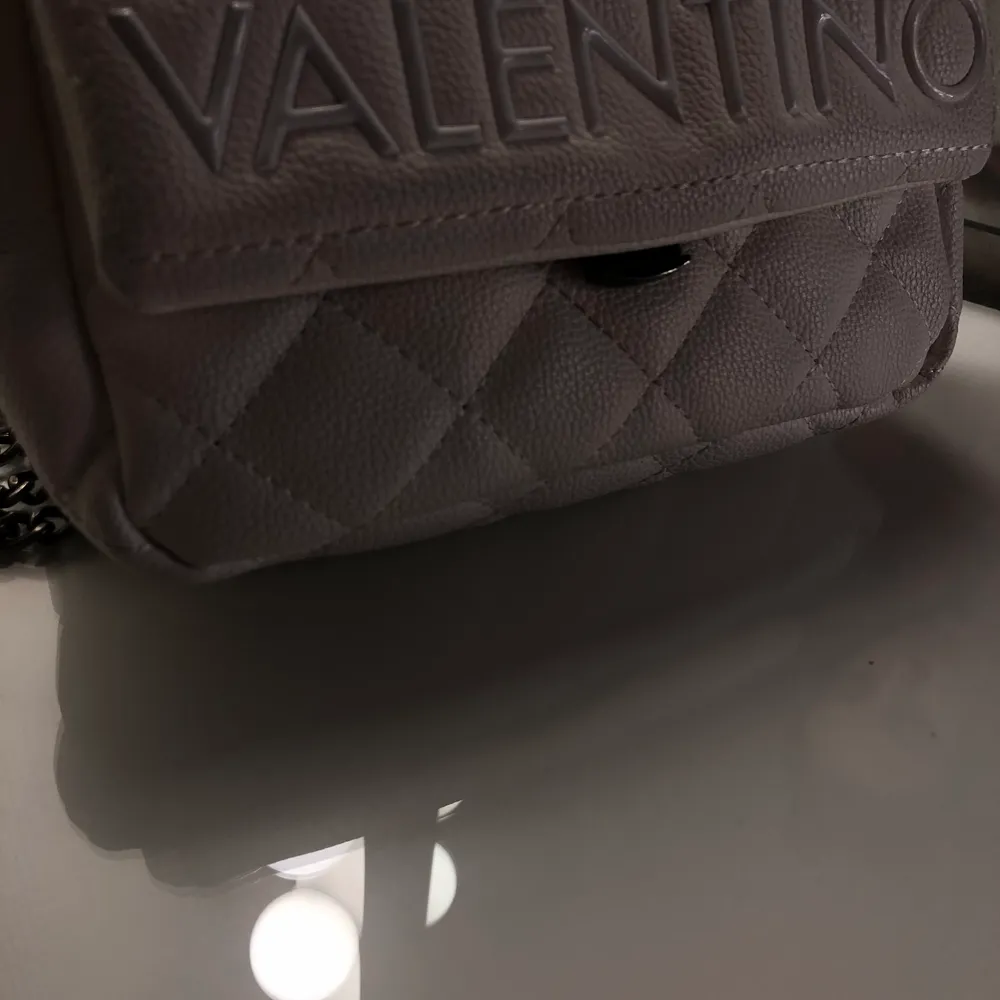 Äkta Valentino väska.  Fortfarande bra skick, axelväska som går att göra kedjorna längre, säljer på grund av att jag ej använder vita väskor. Köpt för 1099 kr - säljer för 350 kr . Väskor.