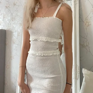 Vit smockad volangklänning - Vit smockad klänning med volang ifrån ASOS, köpt till studenten men säljer då jag hittat annan, lappen kvar och endast testad, storlek XS men passar även S då den är stretchig🥰