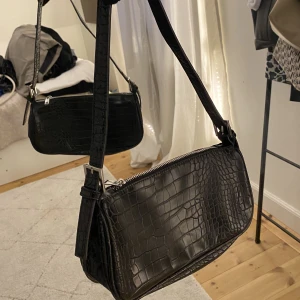 Väska  - Snygg svart axelremsväska från Gina tricot med krokodilmönster och silver detaljer.