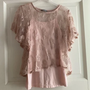 Linne i spets  - Ett puderrosa linne med tillhörande spetstopp över. Spetsen är också puderrosa med silvriga inslag. Storlek 170, men är stort för sin storlek och är som en XS/S. 30kr. 