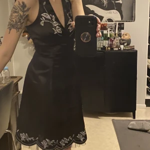 Halterneck klänning - Svart halterneck klänning med broderat fint mönster i silver samt pärlor säljes då den tyvärr inte kommer till användning längre. Öppen rygg! Perfekt skick. Köpt secondhand! Kan mötas upp i Göteborg! Strl S. Knyts i nacken och har dragkedja på baksidan!<3