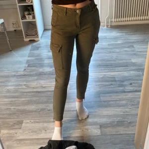 Cargo byxor  - Mörk gröna cargo byxor med dragkedja längst ned, fickor på sidorna.  Lågmidjade. Aldrig använda, storlek s men skulle mer säga att det är xs 