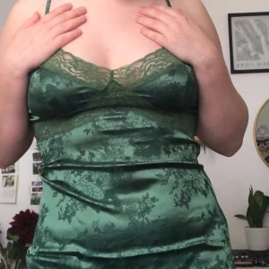 Vacker mörkgrön satin klänning - Super snygg mörkgrön klänning i satin. Köpt från shein ”Romwe collection”. Klänningen har en drag kedja längs sidan.  Använd ett fåtal gånger.  Betalade ca 200kr för den. Säljer den för 100kr.  Köparen står för frakten💜 