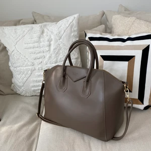 Chiquelle läderväska  - Väska i äkta läder med dubbla handtag ifrån Chiquelle. Försluts med guldfärgad dragkedja. Innehåller ett stort fack och tre mindre innerfack varav ett försluts med dragkedja. Axelrem medföljer.   Färg: Mörk beige  Nypris: 1499kr   Längd 30 cm (max 41 cm). Höjd 30 cm. Bredd 19 cm. 