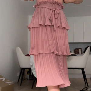 Rosa volangkjol - En rosa volangkjol i en lång modell. Storlek 34 från Gina Tricot. Elasticiteten samt den justerabara bandet i midjan gör så den passar fler storleker. Bara använd vid ett fåtal tillfällen så fortfarande i bra skick.