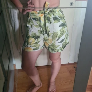 Shorts - Sköna sommarshorts i Lyocell och viskos med band i midjan och dragkedja. Motiv är citronbuskar med vit bakgrund. Storlek 38, funkar för 36 också.