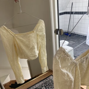 Gul topp med puffärmar - Gul croppad topp med puffärmar och texturerat blommönster. Tröjan är storlek xs men passar s