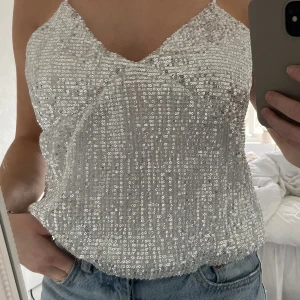 Glitter topp - Perfekta festtoppen!!✨toppen är ifrån NA-KD i gott skick!! Silvrig med massor av paljetter. Säljer då den inte kommer till användning 