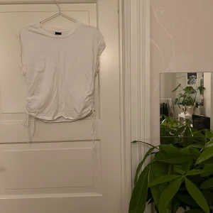 Vit topp🤍 - Vit topp med knytdetalj på sidorna. En söm i mitten både fram och bak. Från Ginatricot, storlek M. Använd men i gott skick. Kan mötas i Göteborg eller skicka, köparen står för frakt. 