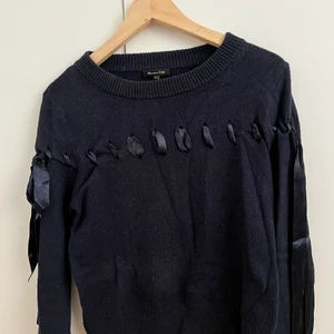 Stickad tröja med band - Tröja från Massimo Dutti i marinblått. Går ett trätt band genom hel tröjan som man kan knyta i rosetter på sidorna. Väldigt gullig och mjuk. Något använd och lite nopprig på vissa ställen. Ull, bomull och akrylblandning💙