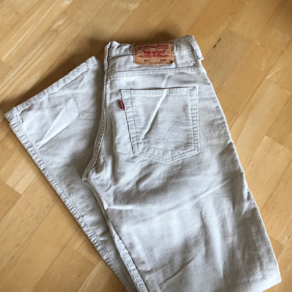 Väldigt fint skick på dessa beige/vita Levi’s manchesterbyxor i modellen 507. De är sparsamt använda av mig, då de var något tajta för min smak. Ena bandet har dock lossnat som man ser på bild 1&3, men det går snabbt att laga med några stygn! Jag är 170cm och på mig sitter dem perfekt i längden!. Jeans & Byxor.