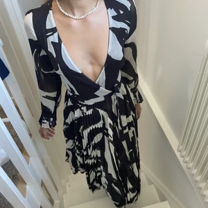 Svart & Vit Sommarklänning  - Superfin sommarklänning i vitt och svart från H&M. Knappt använd då den är för liten. Modellen på bilden bär S men klänningen är i storlek 34. Således varierar urringningen beroende på vilken storlek du har. 
