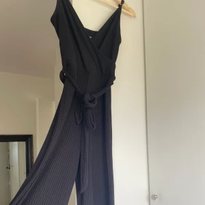 Jumpsuit - Stilig jumpsuit från bikbok med ”bälte” i midjan. Tyvärr har reglaget till ena axelbandet trillat bort lite (se sista bilden) så kan kasa lite, därav priset. Strl S