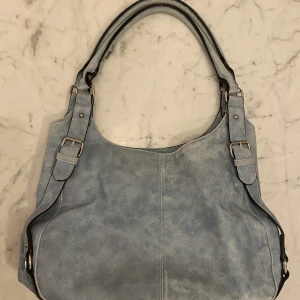 Fin axelväska  - Säljer denna ljusblåaaxelväska med tre fack. Superfin och får plats med lite böcker och pennor osv! Skriv för fler bilder :)🫶🏽