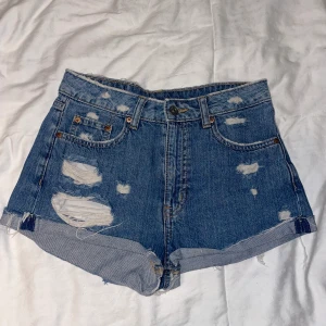 Blåa jeansshorts - Blåa slitna jeansshorts från H&M. Storlek 36.