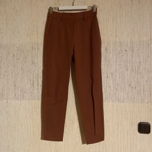 Brun kostymbyxa - Kostymbyxa i slim fit i en koppar-brun färg. Resår baktill och sldrig använd.