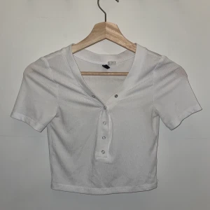Vit tröja - Vit tröja med knappar, alla går att knäppa/knäppa upp. Stretchig och lite lätt genomskinlig. Storlek XS men då den är stretchig skulle jag säga att den passar XS-M.