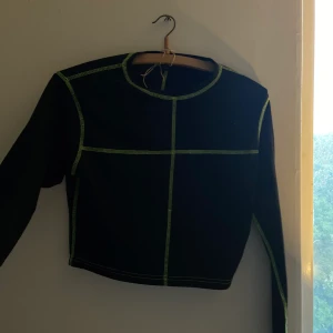 Topp - Svart grön topp, sitter inte jätte tajt på mig och slutar strax över naveln. 