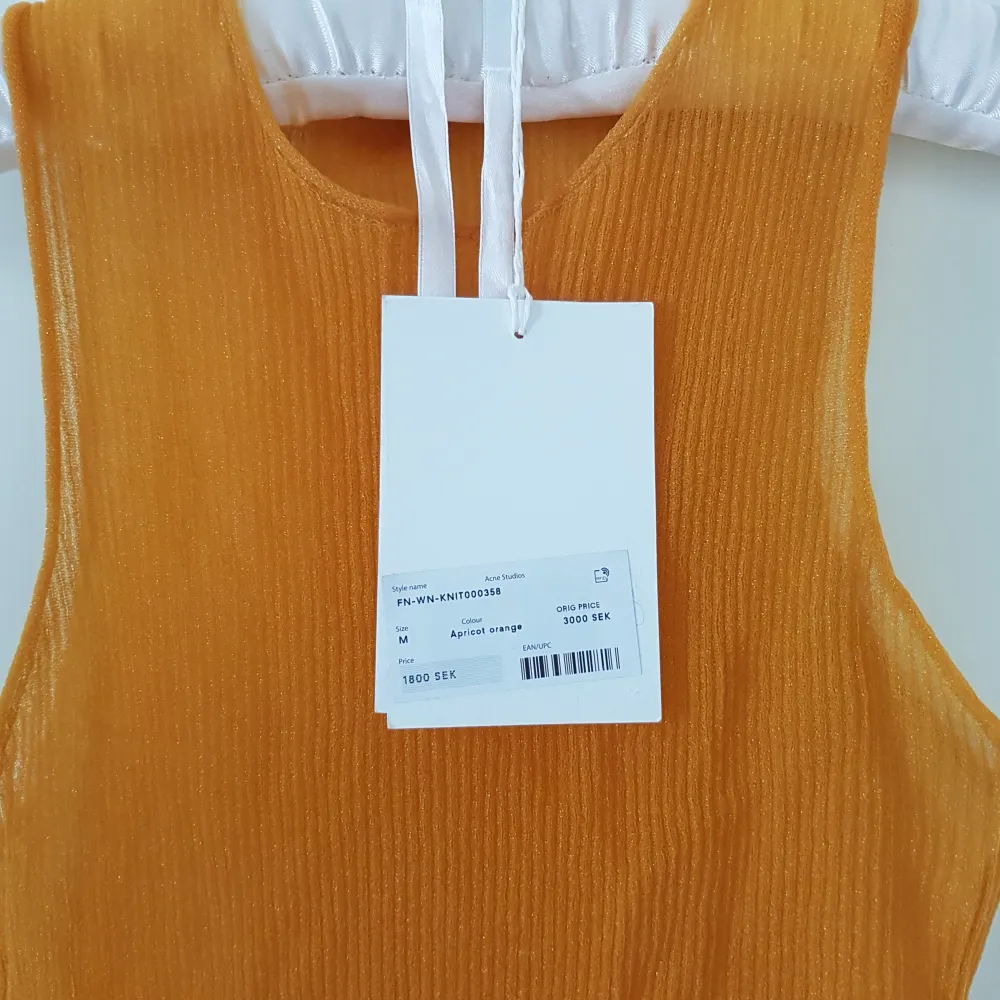 Helt oanvänt halvtransparent linne i ett material som glittrar i solen. Färg: apricote orange Storlek: medium Nypris: 3000 kr.. Toppar.