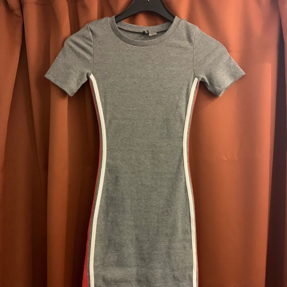 En grå klänning med vita och röda linjer på sidan, köptes på H&M för 149kr || Använt ca 2 ggr || Köparen står för frakt ||. Klänningar.