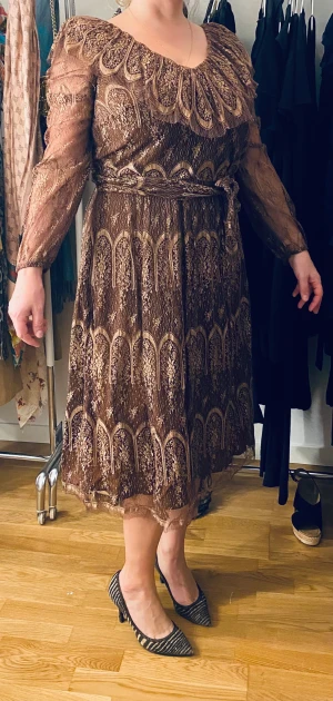 Elegant spetsklänning - Ursnygg och classy klänning i spets. Moccabrun i färg. Sido dragkedja, spets skärp, vacker urringning. Längd till smalbenen. (Jag e 166cm)