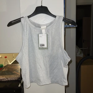 Silver crop top - Croppat glitter linne i stl M från hm. Prislapp kvar. Köparen står för frakt!