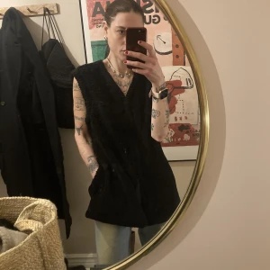 Weekday väst - Luddig Teddy-aktig väst från Weekday strl 38. Figursydd men fickor i sidorna. Snygg att ha som den är eller över tex en tisha/skjorta/trench/kavaj. Mer svart irl. Den vita pricken är endast reflektion. 100% nyskick. 