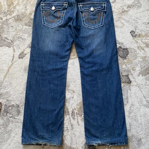 Rhinestone True Religion Bobby Super T jeans W34 - As najs True Religion jeans strl W34 med rhinestones på fickan. Lite slitage på hälarna och några rhinestones fattar men annars bra skick. Hör av er för mer info/bilder, kan mötas i sthlm