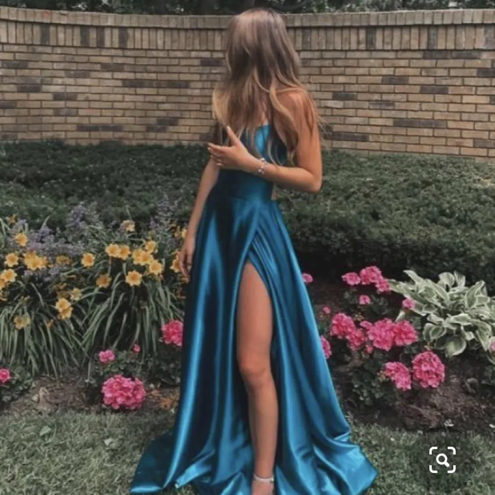 Balklänning från 2022 som är i bra skick. Klänningen är metalliskt ljusblå med en snörad öppen rygg. . Klänningar.