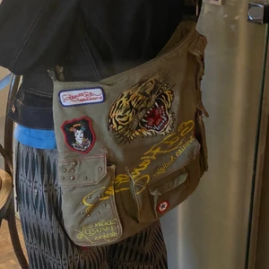 Ed hardy väska - Super fin ed hardy väska med många patches och ett stort brodyr på framsidan samt ett tryck på baksidan.  Öppen till bud och frågor!