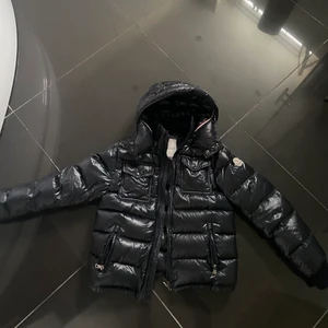 Moncler jacka cappucio - Den har en reva på baksidan ca 3 cm, lagad med lagringslapp i nylon. Lagningen syns inte mycket och förstör inte helhetsintrycket, som ni kan se på andra bilden. 