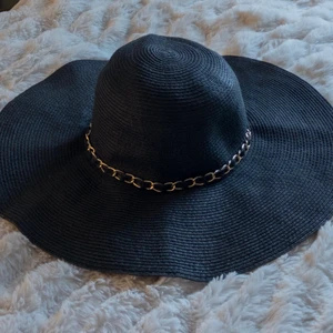 Solhatt från Åhlens - Svart solhatt med guldkedja detaljer, i bra skick fast köptes ett par år tillbaka!🥰 Storlek: one size