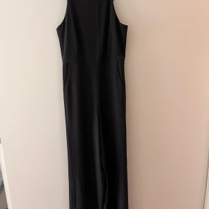 Svart jumpsuit - Svart jumpsuit med vida ben & fickor. Dragkedja baktill. Sparsamt använd men lite slitningar nertill, syns inte när man har den på sig. Strl XS/34. Långa ben. 