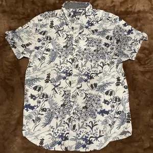 En vit linnen skjorta med blåa blommor i storlek Small regular fit från Dressmann💯
