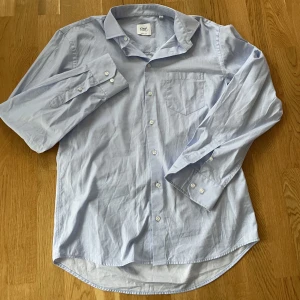 Ljusblå skjorta - Superfräsch krispig ljusblå skjorta!🥰märket är Oscar of sweden och den är endast använd 2 gånger. Nypris är 799kr, sitter lagom oversize på mig som är storlek S
