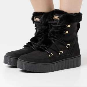 Tommy Hilfiger warm lined lace up bootie strl 37 vinterkängor - Vinterkängor från Tommy Hilfiger. Storlek 37, normal i storlek.  Yttermaterial: skinn och textil. Varmt fodrade av fuskpäls.  Svarta med gulddetaljer.  Skorna har en genomgående platå. Impregnerade. Fint skick, enda är att dom blivit lite glansiga på ytan