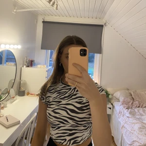 Zebra topp - Säljer denna t-shirt i zebramönster med snörning bak. Den är i ett silkesliknande material och är därav väldigt skön. Den kommer inte till användning här hemma och den är i bra skick. Köpt på Bershka i storlek S men den är cropped🤍 Köparen står för frakt